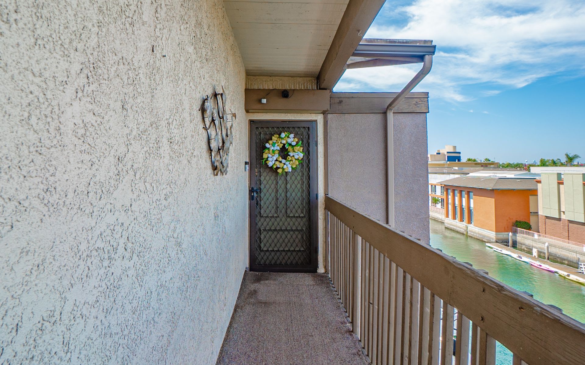 Condominium entry balcony overlooking a canal, with a screened door and waterfront buildings.