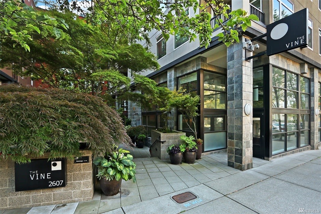 Entrance to The Vine's luxury condos, framed by lush greenery, conveys a tranquil, high-end city living feel.