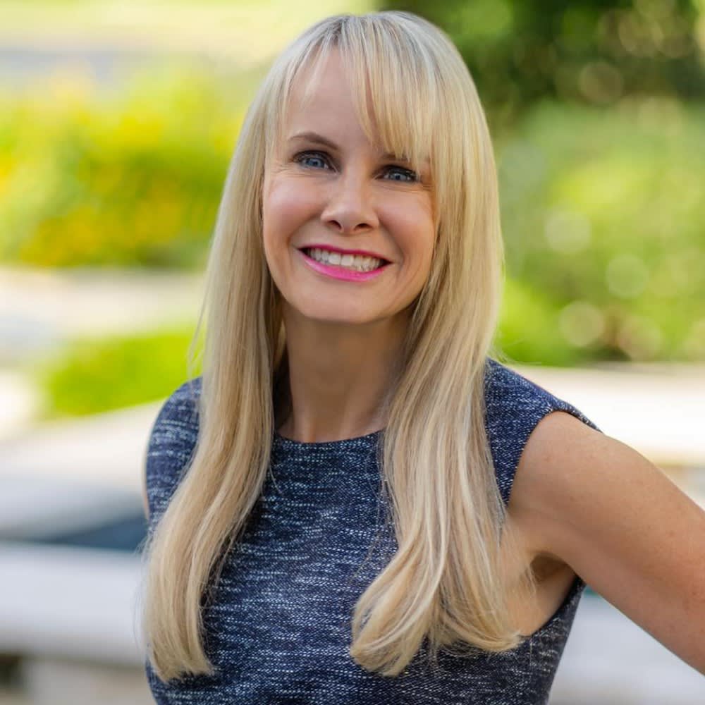 Ally Seder, a smiling real estate professional from The Mike Seder Group, with a blonde hair wearing a blue top.