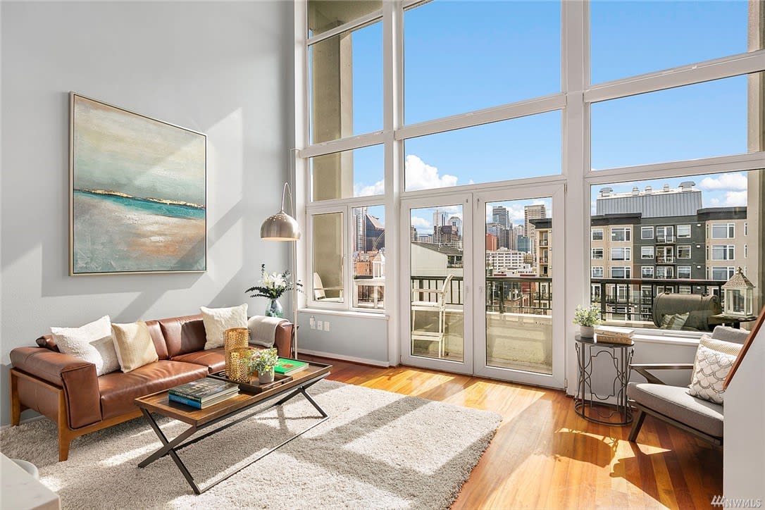 A spacious living room with expansive windows showcasing natural light and a comfortable couch.