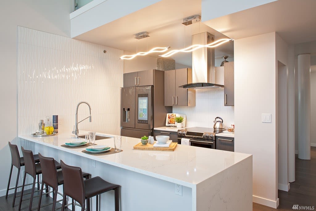 Chic condo kitchen with marble countertops, warm lighting, and sophisticated bar seating.
