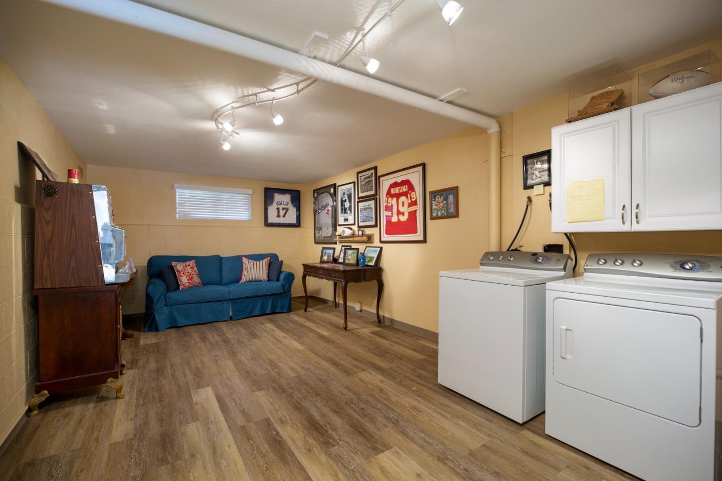 Laundry room with washer and dryer, blue sofa, and framed sports memorabilia.