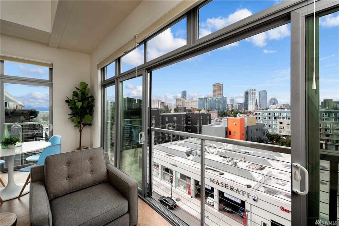 Bright, airy condo living area with floor-to-ceiling windows offering a cityscape view.