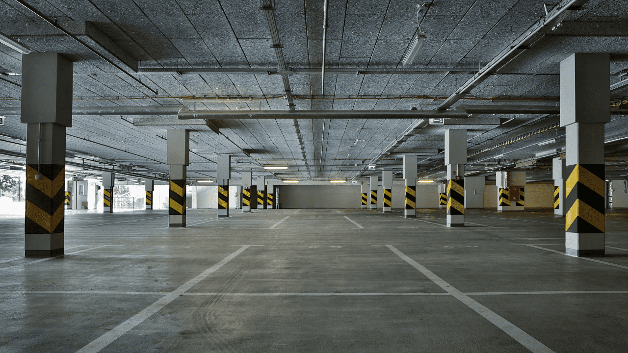 The garage has a concrete floor and ceiling. Numerous concrete support pillars are spaced throughout the garage.