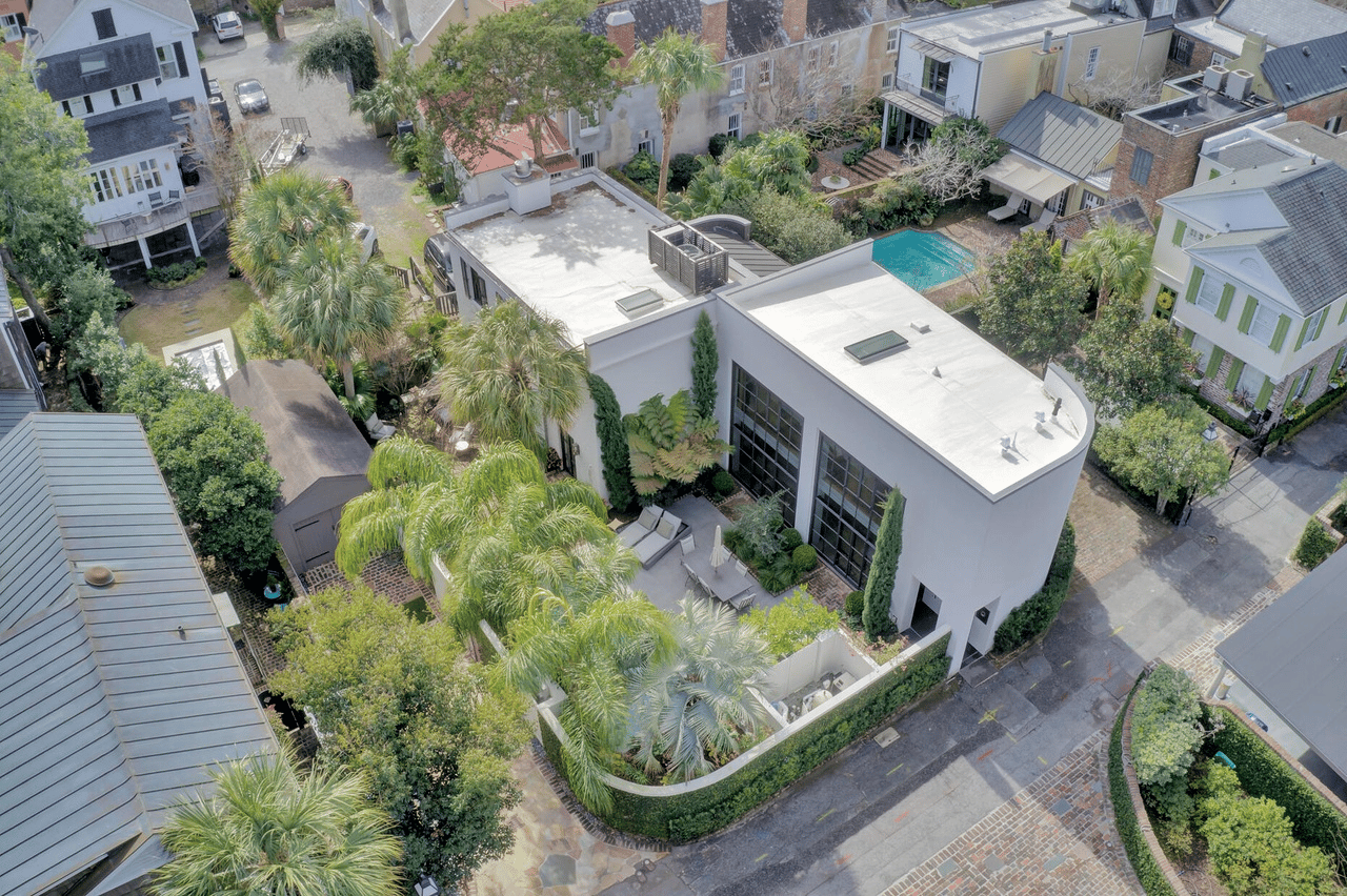 Aerial view of a modern home with a landscaped courtyard, palm trees, and swimming pool.