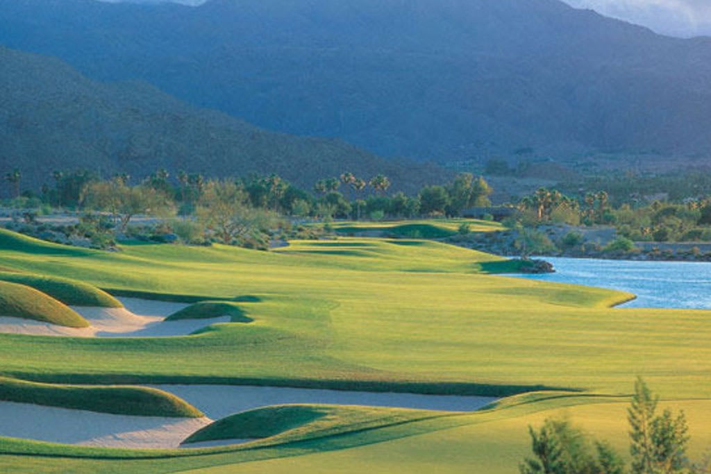 A panoramic view of a golf course with a lake.