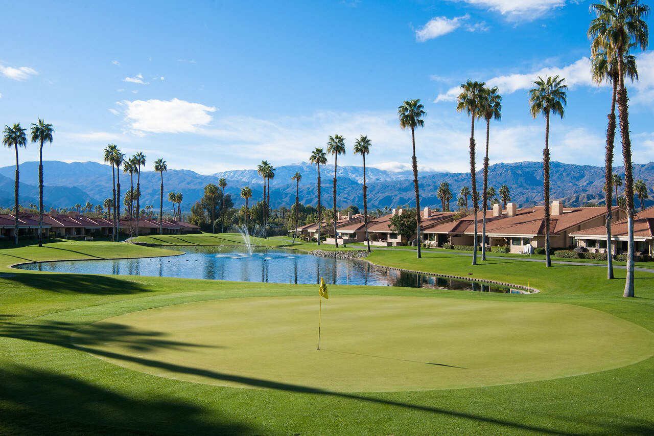 A golf course with a pond and palm trees