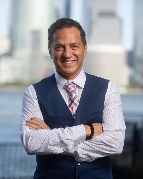 Francesco Mazzaferro, a professional real estate professional in a vest and tie, with the city in the background.