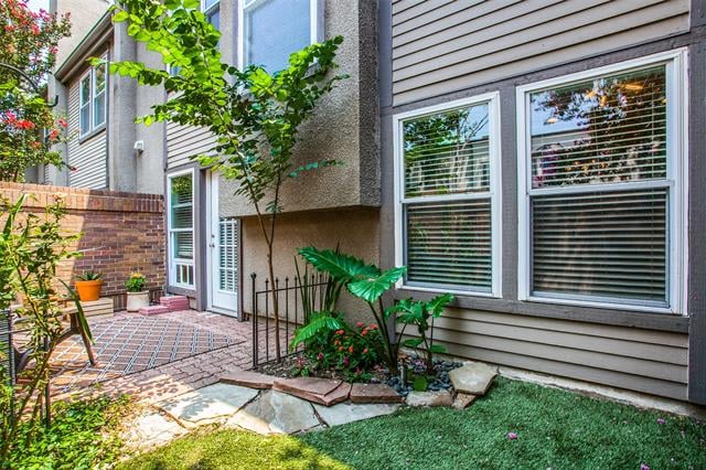 Townhouse exterior with a brick patio, landscaped courtyard, windows, and glass entry doors.