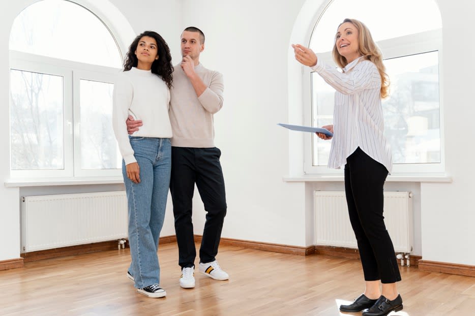 female real estate agent showing couple the property