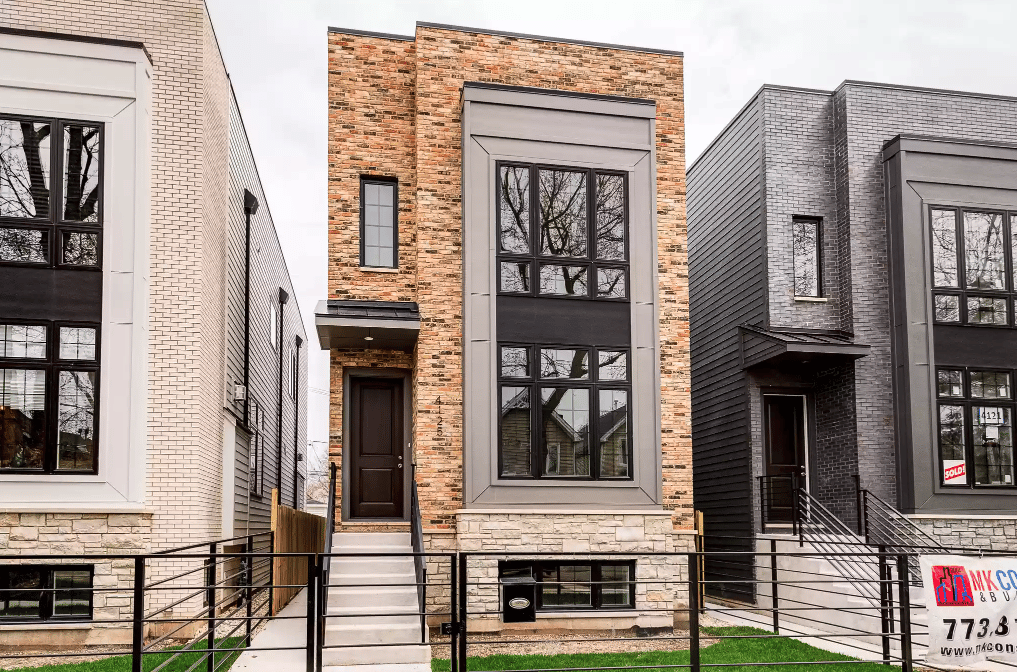 Modern attached townhomes with a red-brick center facade and a SOLD sign in the right-hand window.