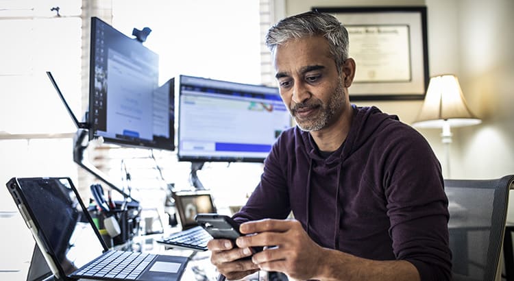 A man working at his desk with multiple computer screens, indicating themes related to work, technology, or productivity.