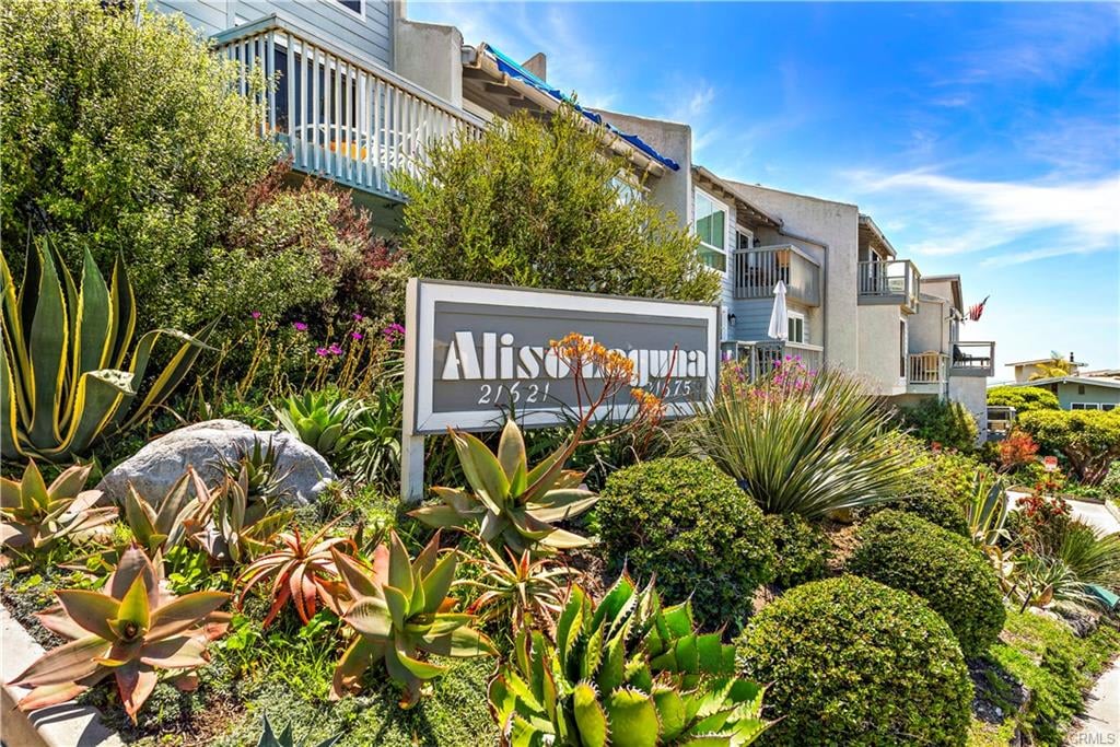 Multi-unit building with balconies behind a landscaped succulent garden and monument sign.