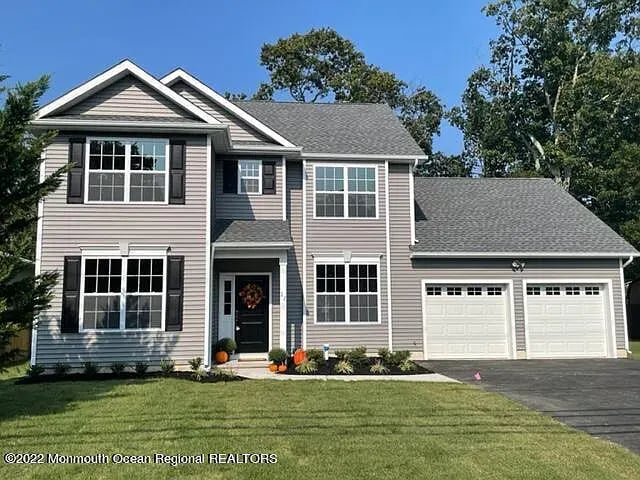 Two-story gray house with a double garage and a well-maintained lawn.