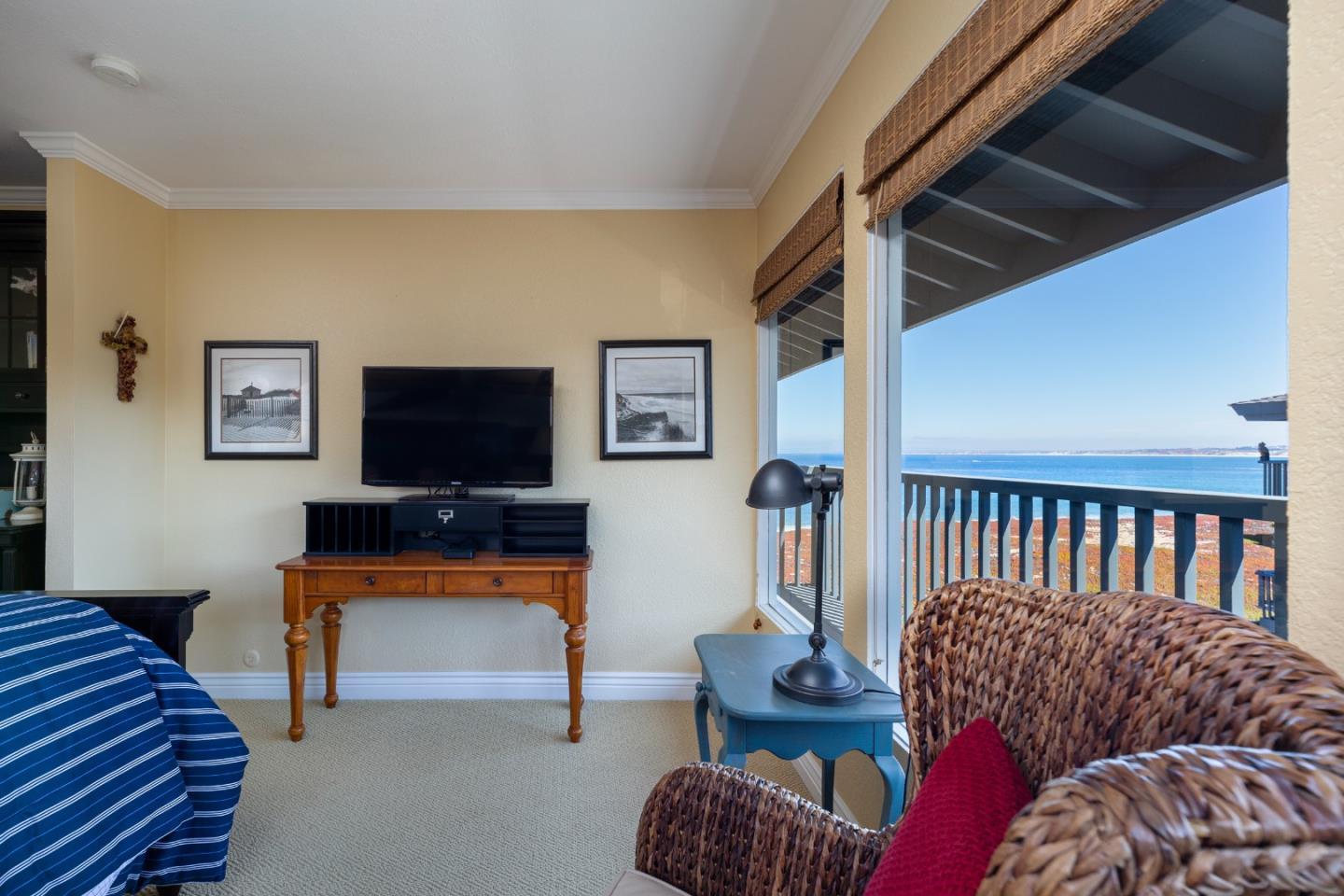Bedroom with wicker seating and large windows overlooking the ocean.