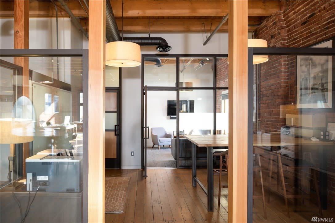 Elegant loft with wooden beams, glass partitions, and an open office setup.