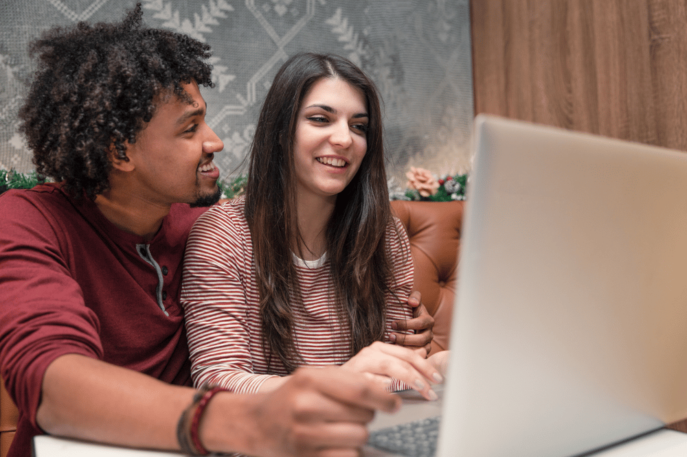 Couple on a sofa browsing homes together on a laptop.