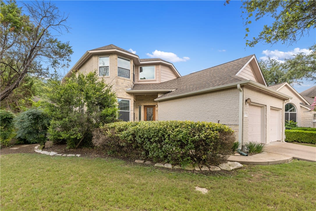 Two-story brick house with an attached garage and landscaped front yard.