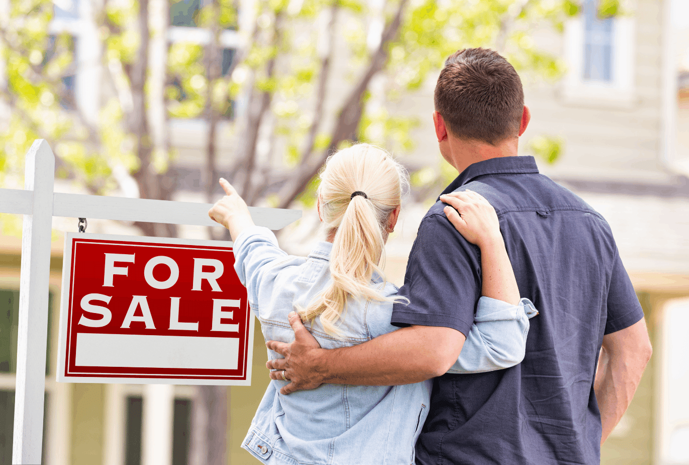 A couple looks toward a house beside a red FOR SALE sign.