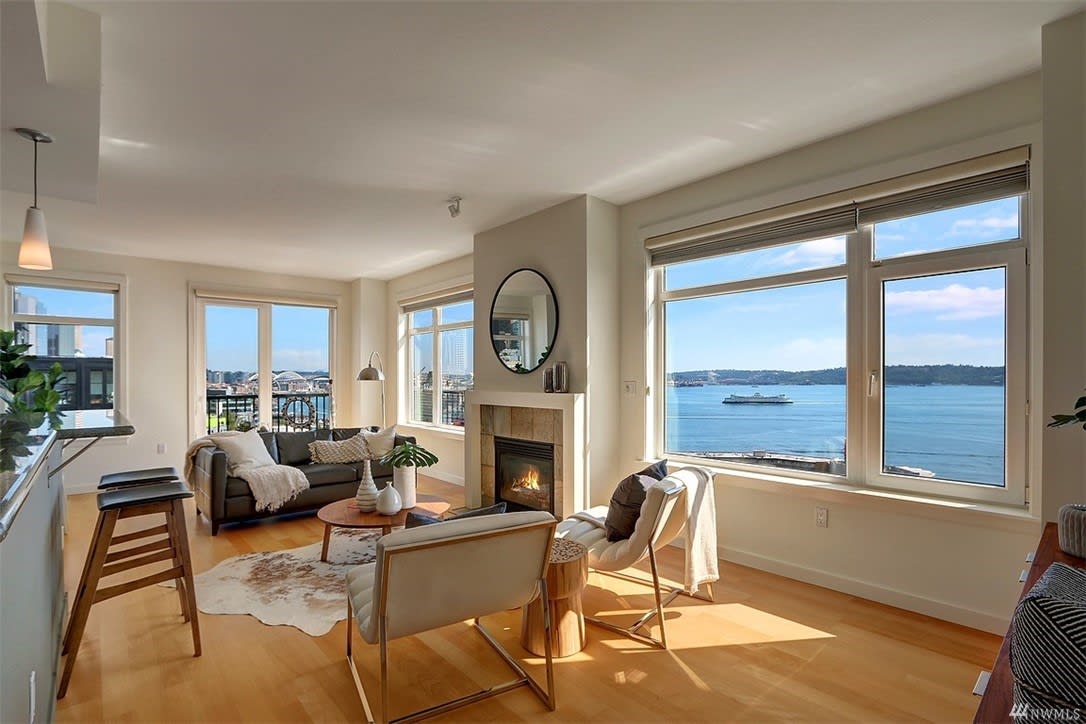 Bright, elegant condo living room with fireplace and expansive water views, embodying luxury and tranquility.