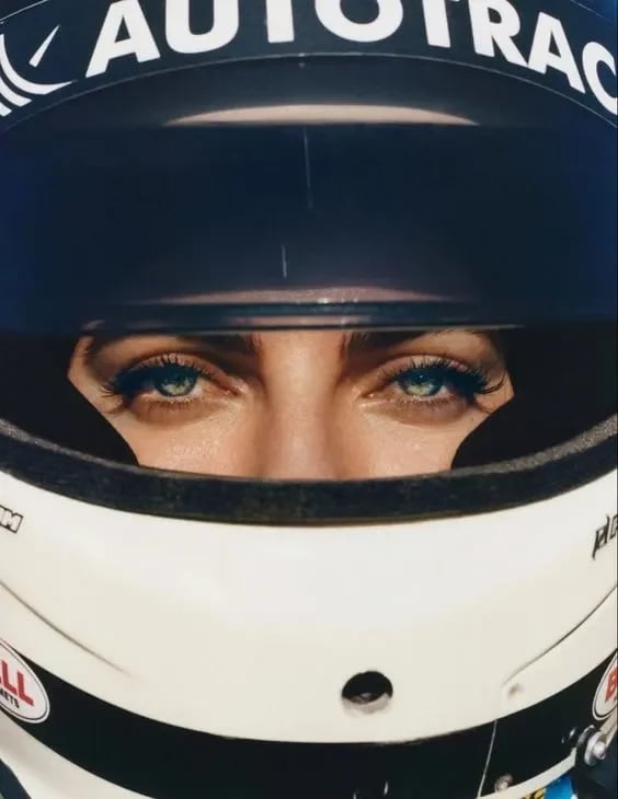  A tight, close-up shot focuses intently on a person's eyes, framed by a racing helmet. 