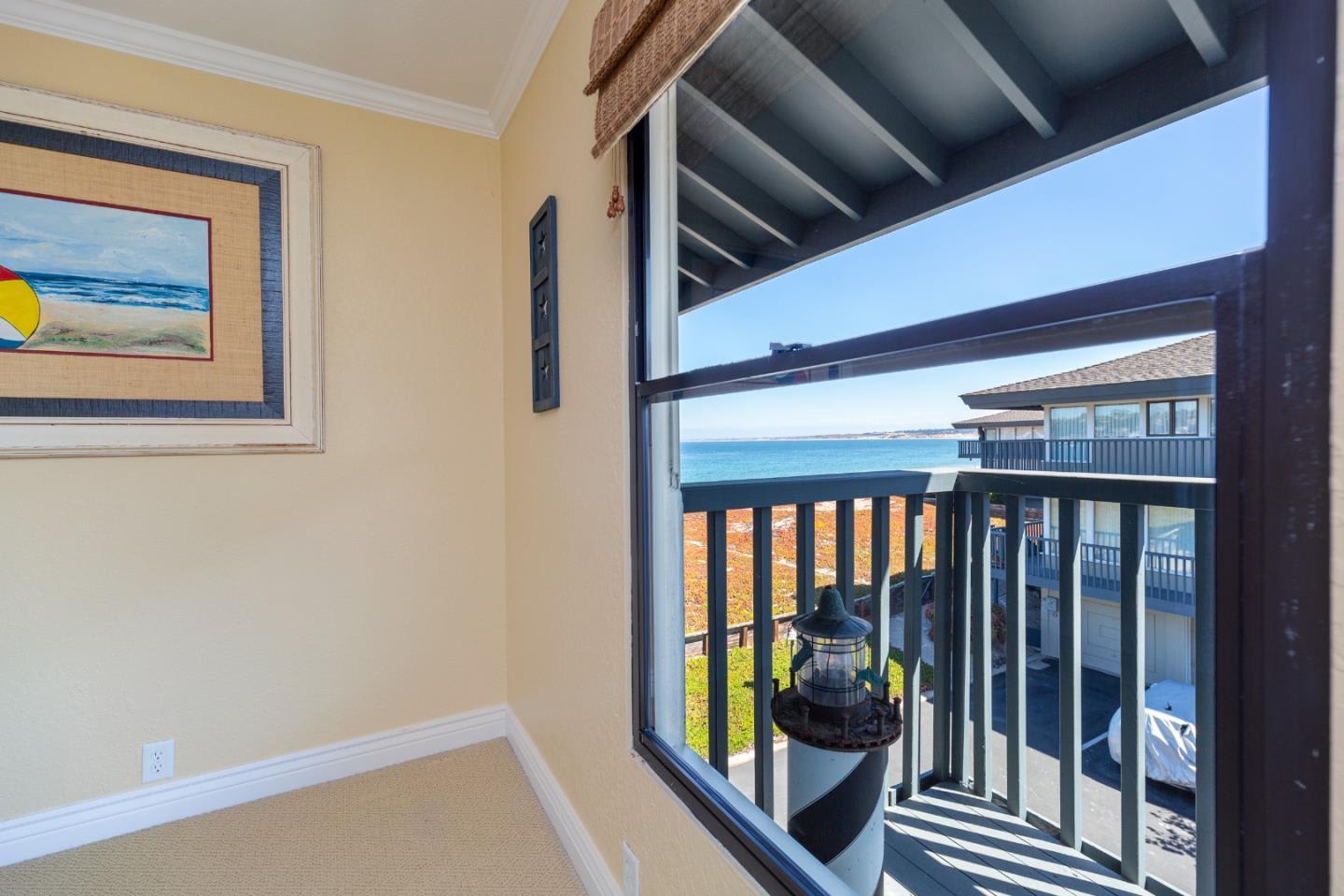 Room with a large window overlooking the ocean and a balcony.