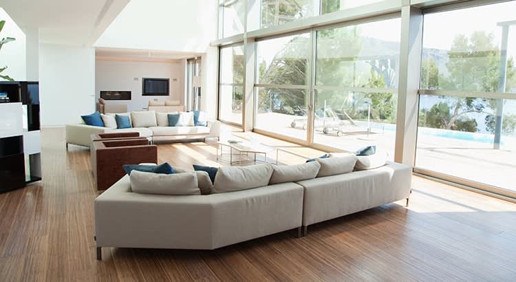 A bright, spacious living room with large windows that let in plenty of natural light. The room is well-decorated with neutral tones and contemporary furniture.