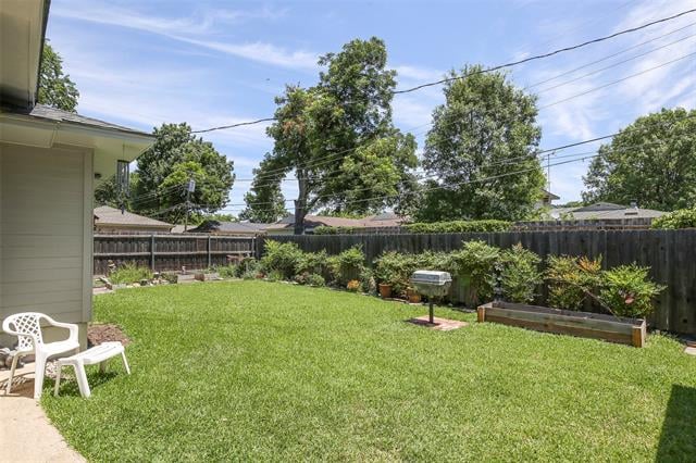 Fenced backyard with a broad lawn, raised garden beds, and a barbecue grill.