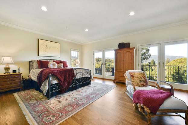 Furnished bedroom with a wrought-iron bed, hardwood floors, and glass doors opening to a balcony.