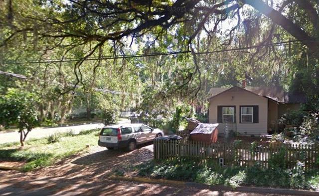  A picture of a house with a unique architectural style, featuring a curved entrance path and surrounded by trees.