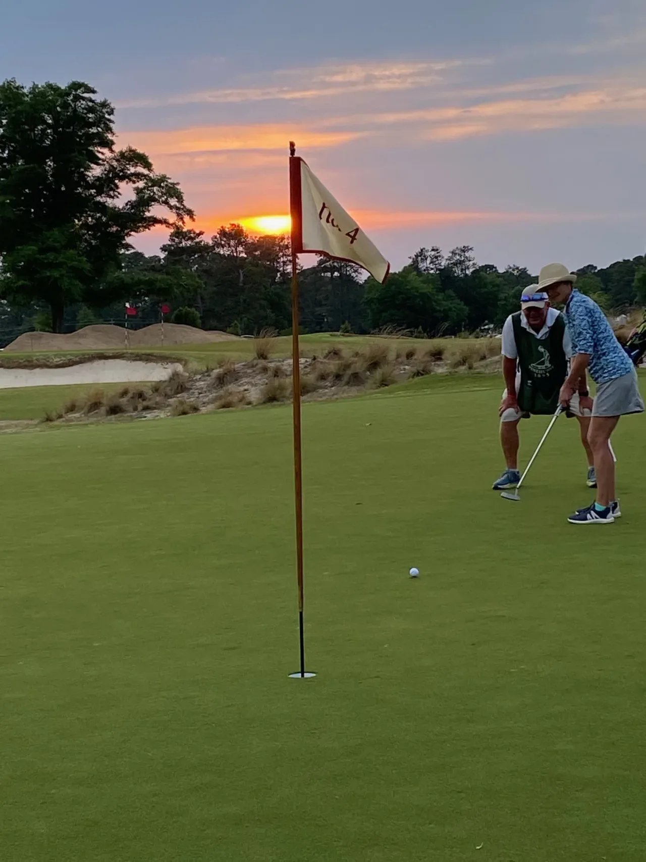 Two golfers enjoy a friendly game as the sun sets.