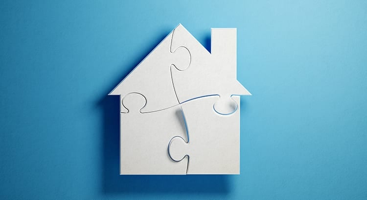 A house puzzle on a blue background, symbolizing the concept of putting together the pieces of homeownership or real estate decisions.