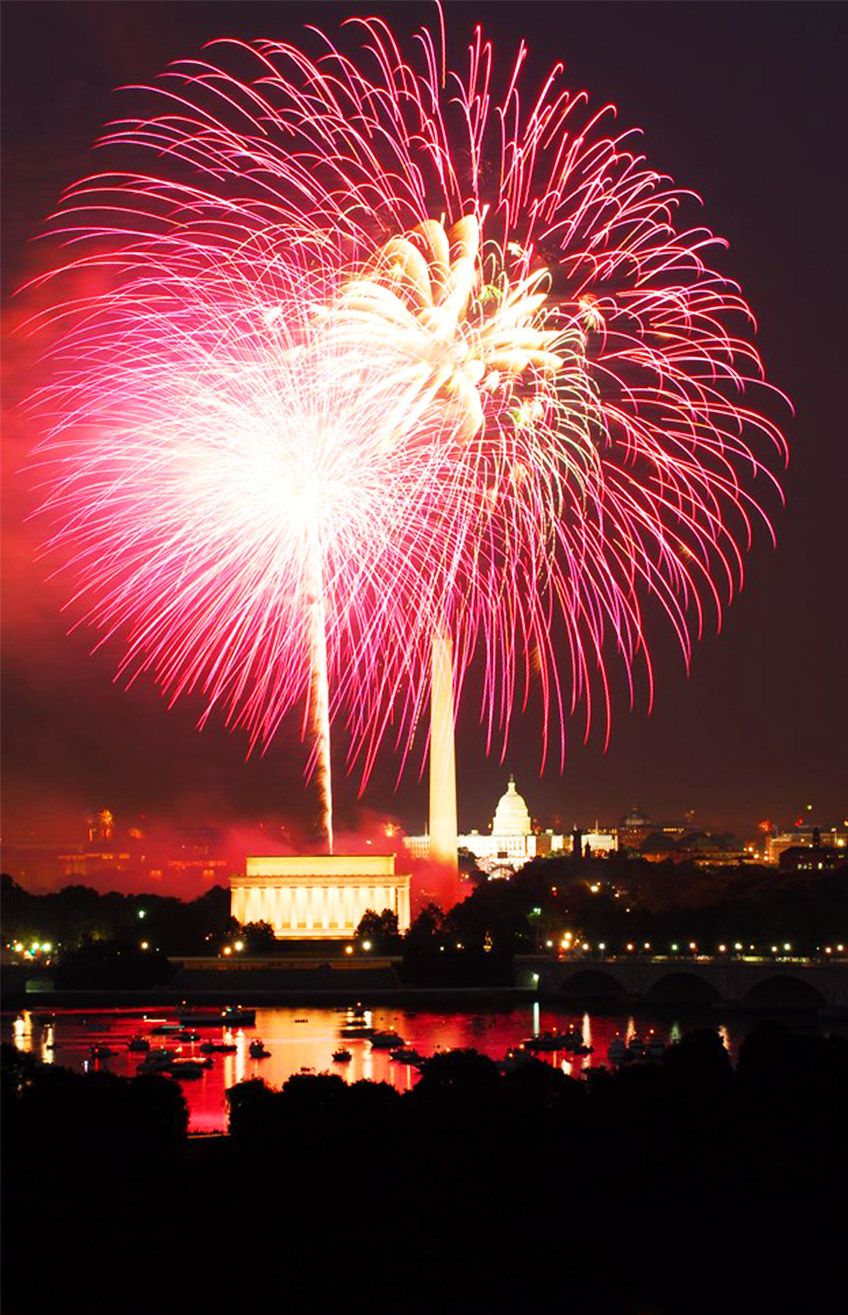 Fireworks over Washington, D.C., with the Lincoln Memorial and Capitol illuminated above the Potomac.