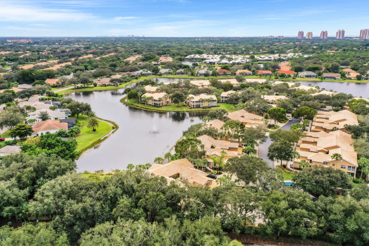  An aerial view showcases a sprawling residential community interspersed with numerous lakes and lush green trees.