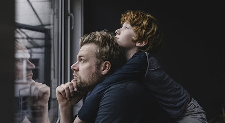 A close-up of a man with a thoughtful expression, with a child close by, creating a tender, introspective moment.