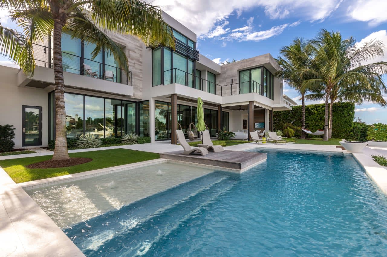 A stunning luxury estate with a glistening pool and tropical palms.