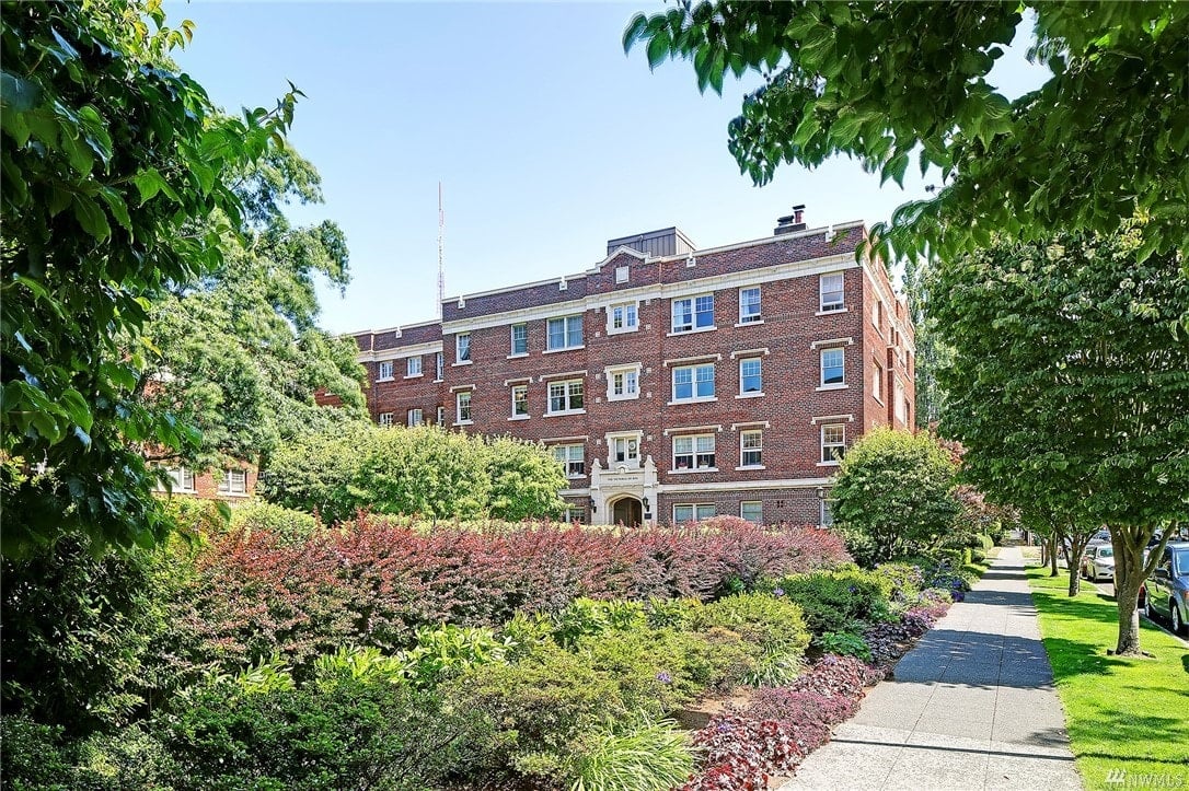 Historic luxury condo building nestled in lush landscaping, radiating charm and exclusivity.