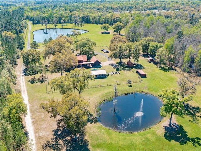 An aerial view of a large property in 2665 Aucilla with multiple buildings, a pond, and a mix of open grassy areas and trees. The setting suggests a rural location with expansive land.