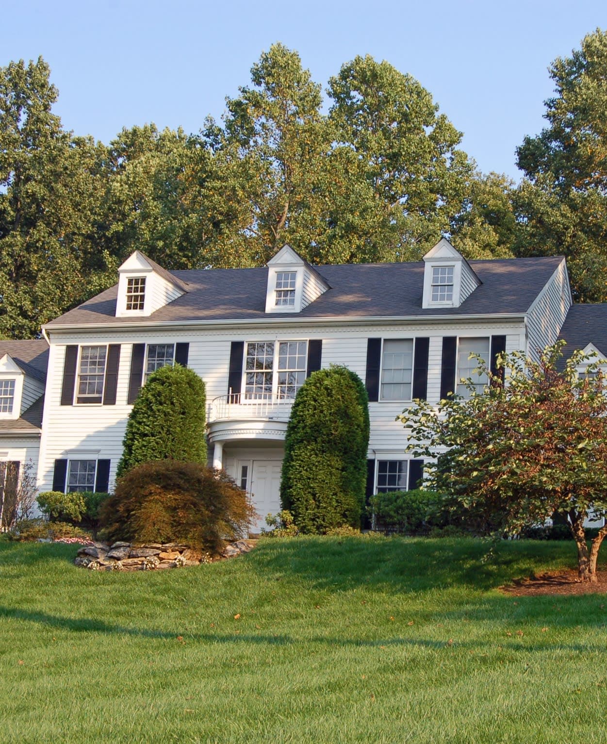 A white house with black shutters and a lush green yard in Philadelphia. 