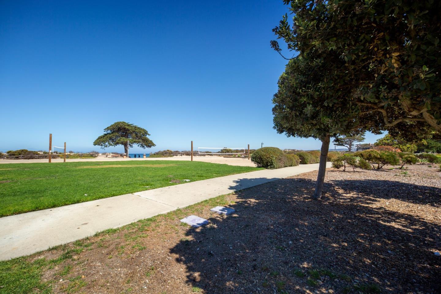 Coastal park with volleyball nets, a walkway, and a glimpse of the ocean