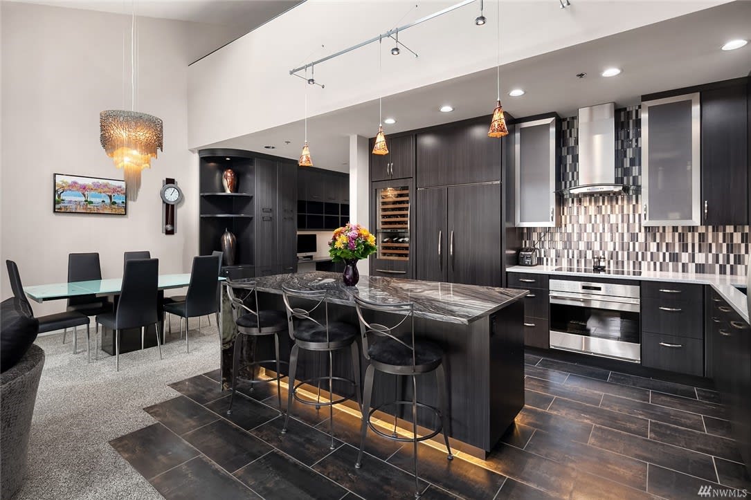 Elegant kitchen featuring black cabinets and a modern bar.