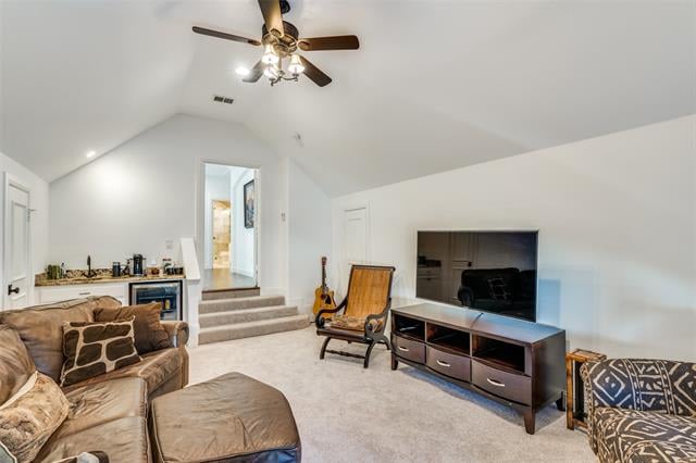 Living room with vaulted ceiling, leather seating, television, and a small kitchenette.