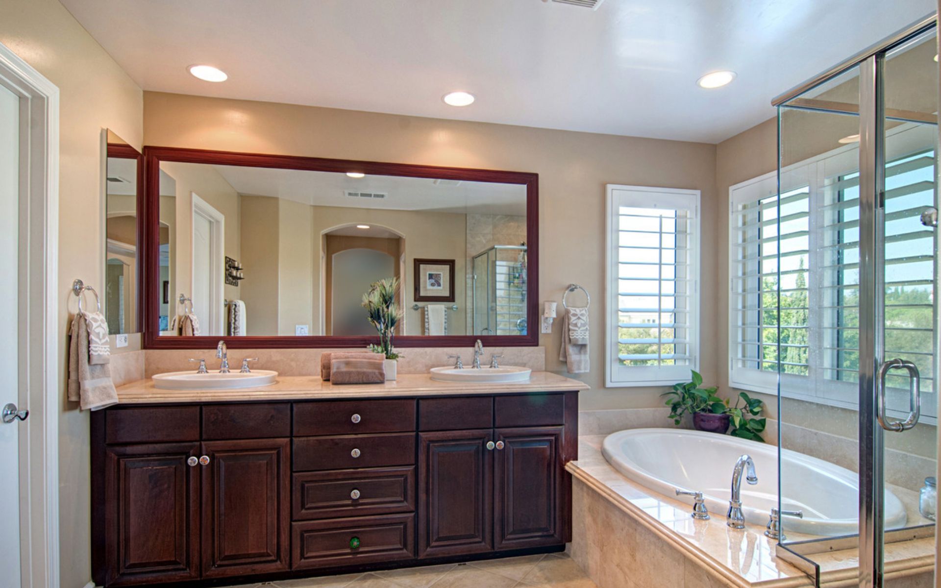Spacious bathroom with a dark wood double vanity, soaking tub, and glass-enclosed shower.