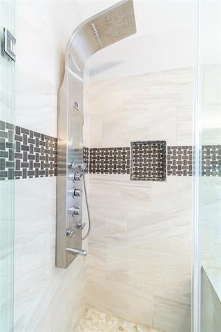 Walk-in shower with a rainfall showerhead, chrome controls, and dark mosaic tile accents.