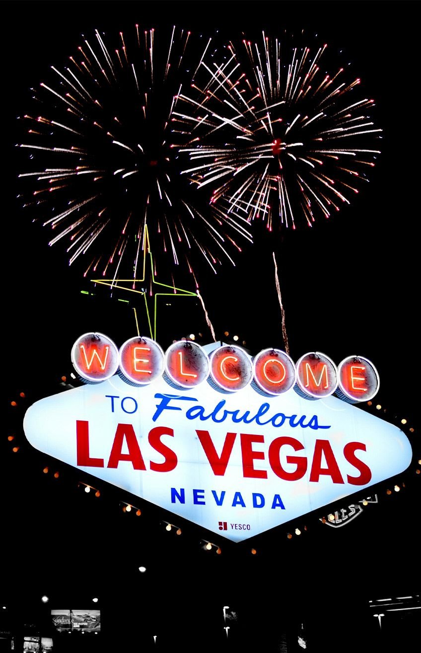 Welcome to Fabulous Las Vegas sign beneath pink and white fireworks at night.
