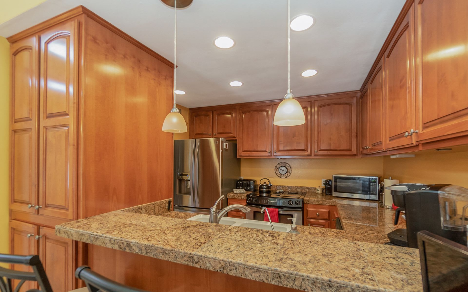 Kitchen with warm wood cabinets, granite counters, and a wide breakfast bar.