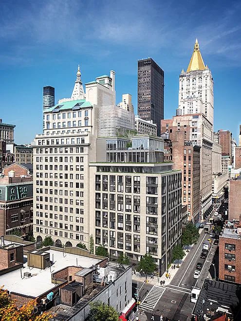 Mid-rise apartment building among Manhattan city blocks beneath a clear blue sky.