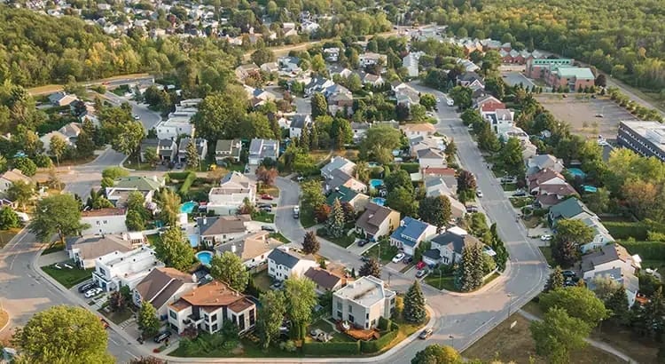 An aerial view of a residential neighborhood with houses, streets, and greenery. The image highlights suburban living or real estate development.