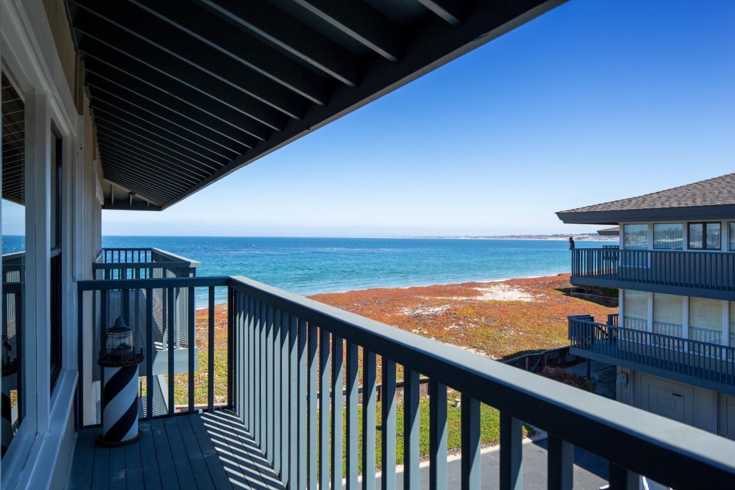 Covered balcony overlooking the ocean and shoreline, framed by dark railings.