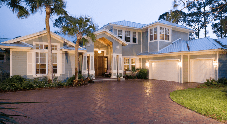 A spacious home featuring a driveway lined with palm trees, showcasing a tropical and inviting atmosphere.